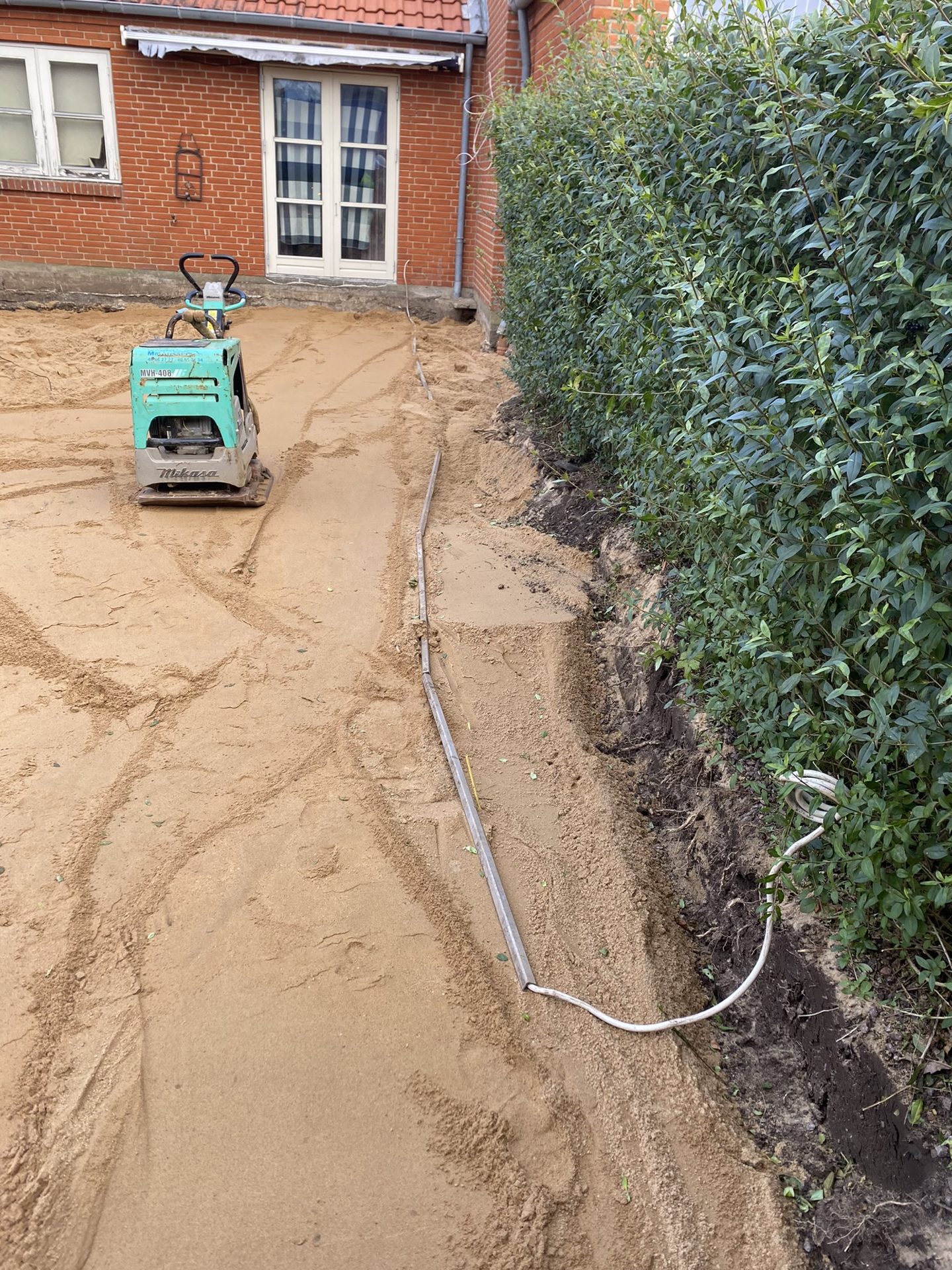 Sand komprimeres med pladevibrator